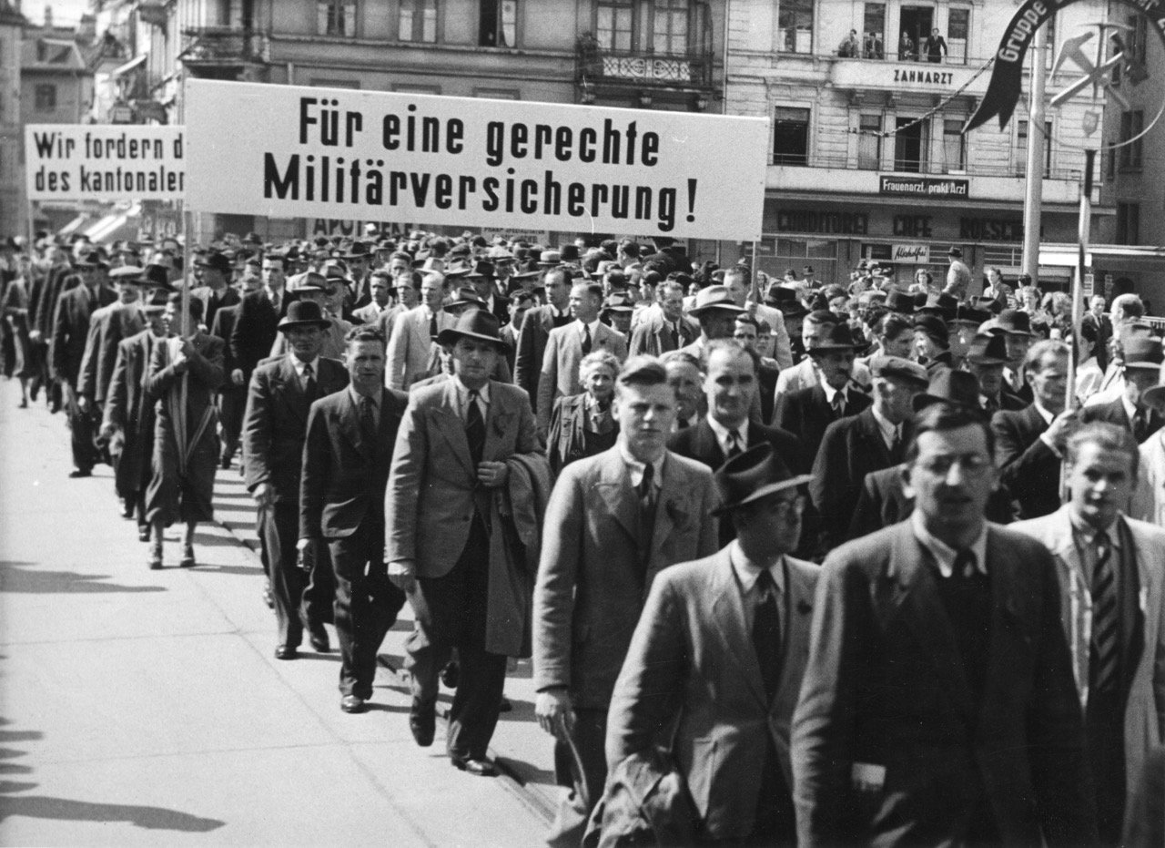 Défilé du 1er Mai avec bannière: «Pour une assurance militaire équitable!». Source: Archives sociales suisses, Zurich, Sozarch_F_5047-Fb-090.
